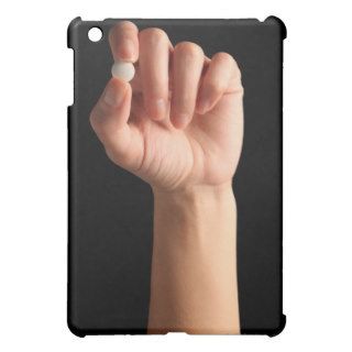 Persons hand holding a white pill between the iPad mini case