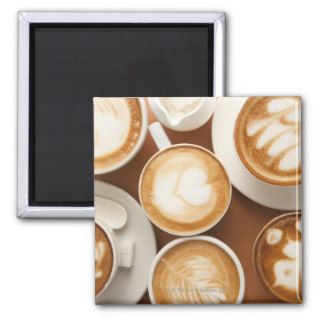 Close up of cups of cappuccino with different fridge magnet