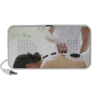 Woman having hot rock massage at spa travelling speakers