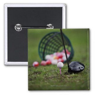 Golf ball on tee beside golf club pinback buttons